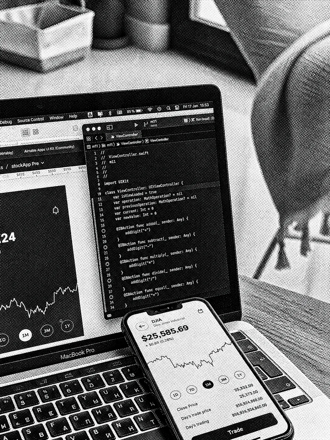 A laptop running an IDE beside a phone showing a live market chart.
